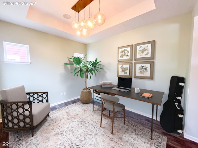 office with hardwood / wood-style floors, a tray ceiling, and a notable chandelier