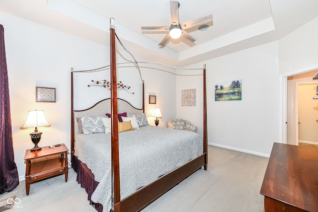 carpeted bedroom with a raised ceiling and ceiling fan