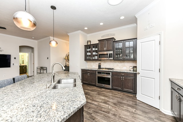 kitchen featuring sink, dark brown cabinets, stainless steel appliances, light stone countertops, and decorative light fixtures