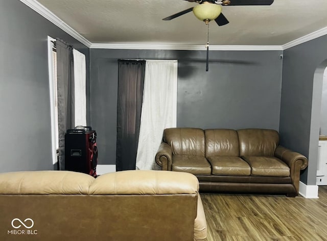 living room featuring ceiling fan, ornamental molding, and wood-type flooring