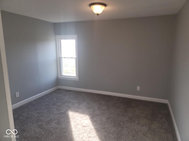 spare room with dark colored carpet