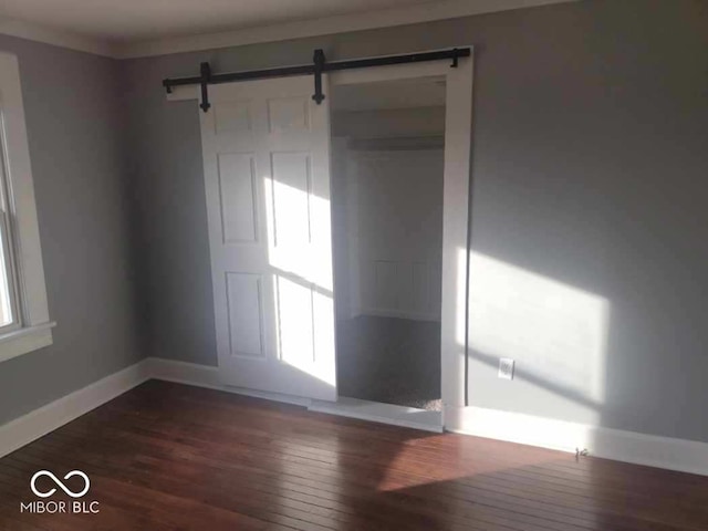 unfurnished room with a barn door and dark hardwood / wood-style flooring