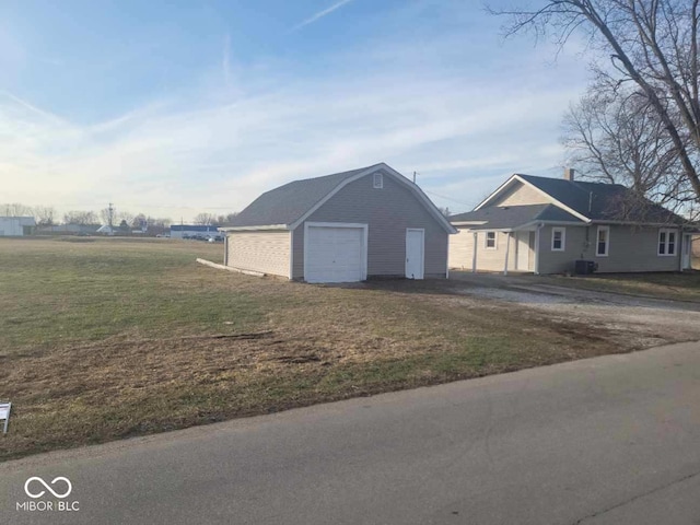 exterior space with a garage, an outbuilding, central AC unit, and a front lawn