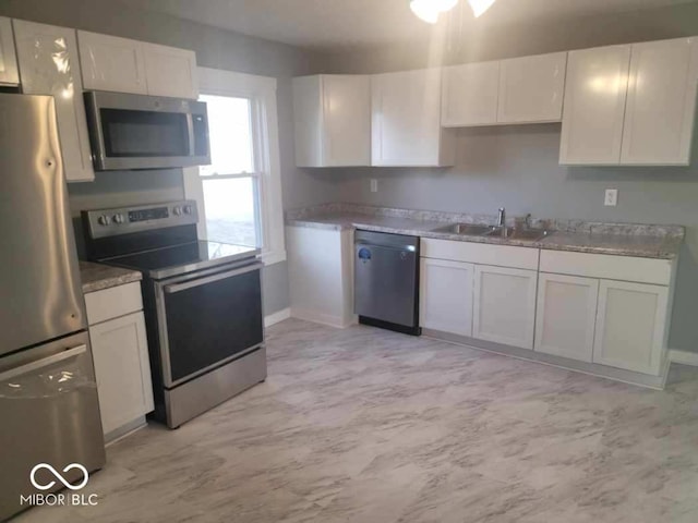 kitchen with light stone countertops, appliances with stainless steel finishes, sink, and white cabinets