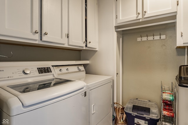 laundry room featuring washer and clothes dryer and cabinets