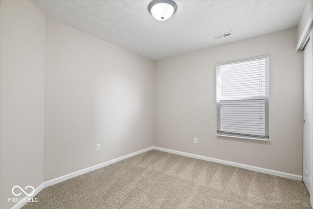 carpeted empty room with a textured ceiling