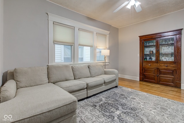 living room with ceiling fan, light hardwood / wood-style floors, and a textured ceiling