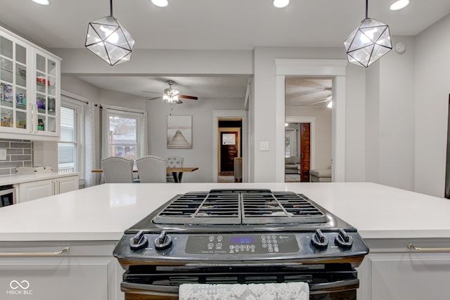 kitchen with white cabinetry, pendant lighting, ceiling fan, and gas stove