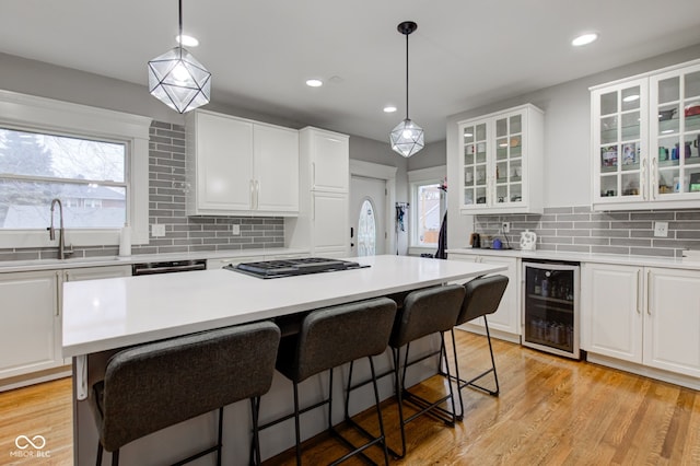 kitchen featuring sink, white cabinetry, a kitchen breakfast bar, a center island, and beverage cooler