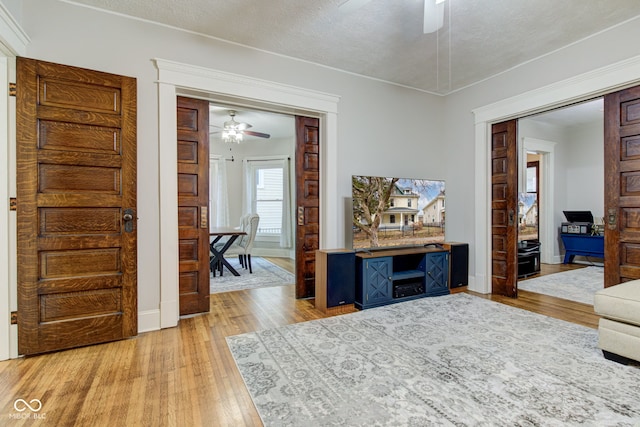 living room featuring ceiling fan, light hardwood / wood-style floors, and a textured ceiling