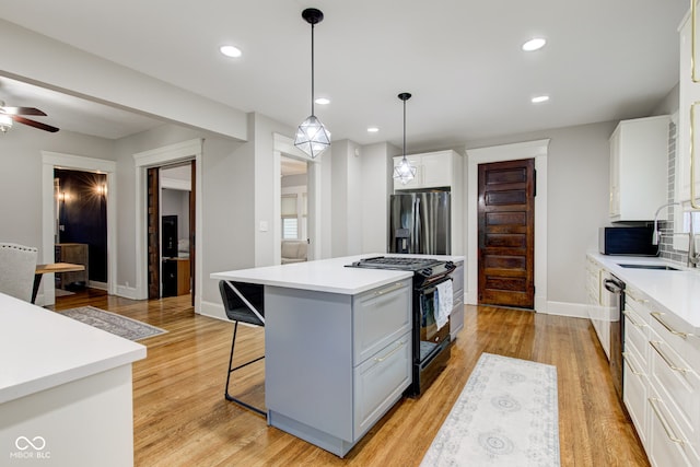 kitchen with sink, decorative light fixtures, a center island, black appliances, and white cabinets