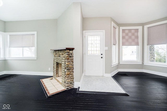 foyer featuring dark wood-style floors, a fireplace, and baseboards