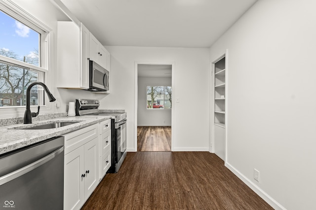 kitchen with sink, white cabinetry, dark hardwood / wood-style flooring, stainless steel appliances, and light stone countertops