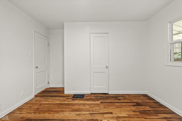 unfurnished room with dark wood-type flooring