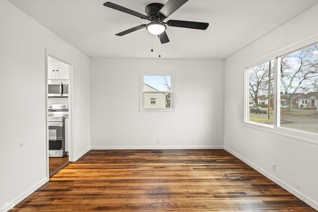 spare room with dark wood-type flooring, a wealth of natural light, and ceiling fan