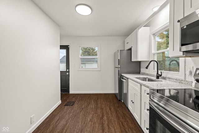 kitchen featuring white cabinetry, sink, stainless steel appliances, light stone countertops, and dark wood-type flooring