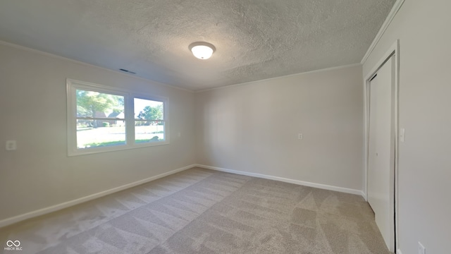 unfurnished room with ornamental molding, light carpet, and a textured ceiling