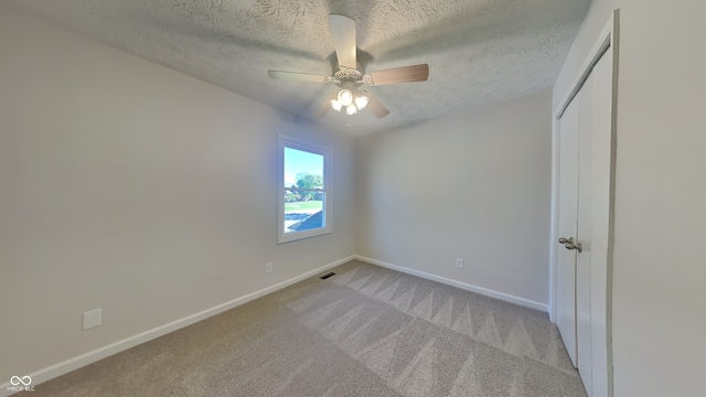 unfurnished bedroom with ceiling fan, light carpet, a textured ceiling, and a closet