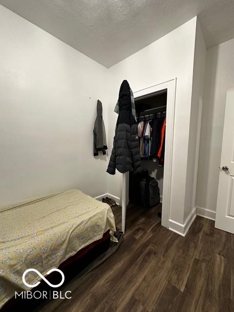 bedroom with dark hardwood / wood-style floors and a textured ceiling