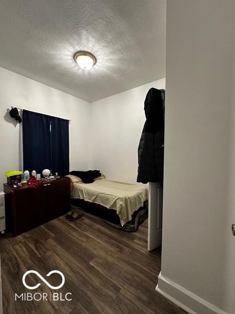 bedroom featuring a textured ceiling and dark hardwood / wood-style flooring