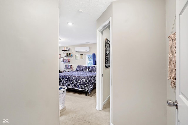 hall featuring light carpet, a wall mounted air conditioner, and a textured ceiling