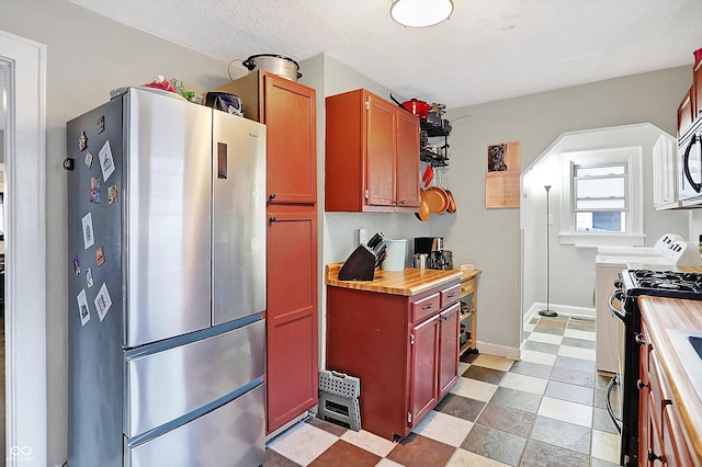 kitchen featuring stainless steel appliances, a textured ceiling, and wood counters