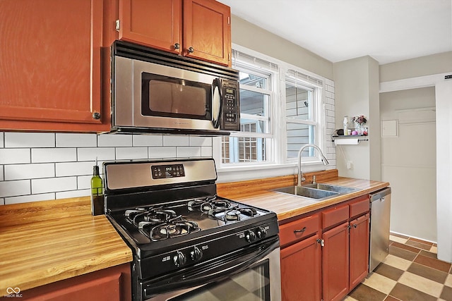 kitchen with stainless steel appliances, sink, wood counters, and decorative backsplash