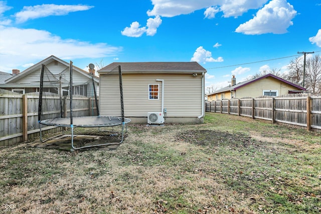 rear view of house with a lawn, a trampoline, and ac unit