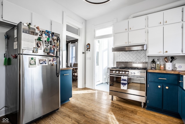 kitchen with blue cabinets, white cabinetry, tasteful backsplash, stainless steel appliances, and light hardwood / wood-style floors