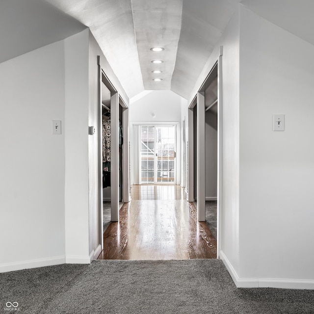 hallway featuring dark carpet and vaulted ceiling