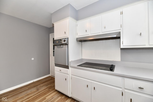 kitchen with white cabinets, backsplash, oven, light hardwood / wood-style floors, and black electric cooktop