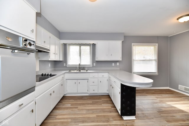 kitchen with white cabinetry, white oven, black electric stovetop, and kitchen peninsula