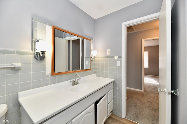 bathroom with vanity, toilet, and tile walls