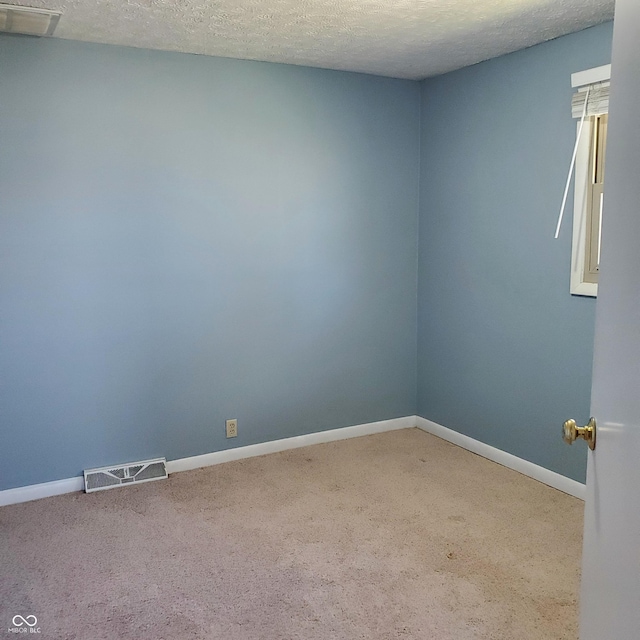 carpeted spare room featuring baseboards, visible vents, and a textured ceiling