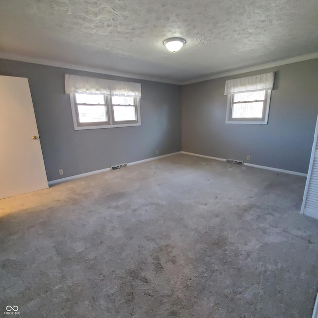 unfurnished room featuring visible vents, crown molding, a textured ceiling, and baseboards