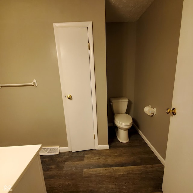 bathroom with visible vents, toilet, baseboards, and wood finished floors