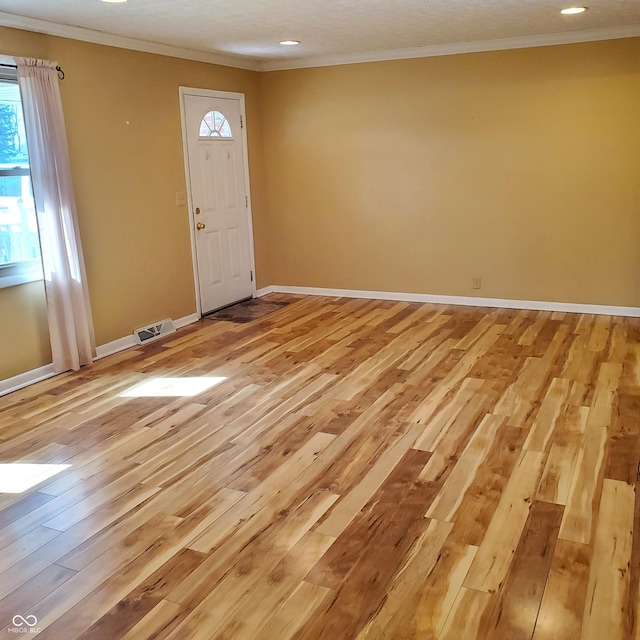 foyer featuring baseboards, light wood-style flooring, visible vents, and crown molding