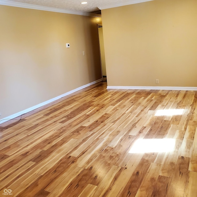 unfurnished room featuring ornamental molding, light wood-type flooring, and baseboards