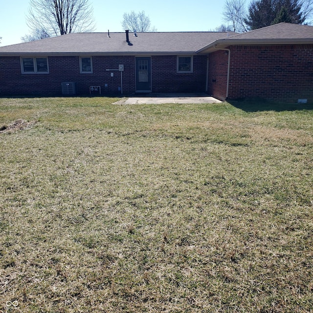 rear view of property featuring a yard, a patio, central AC, and brick siding