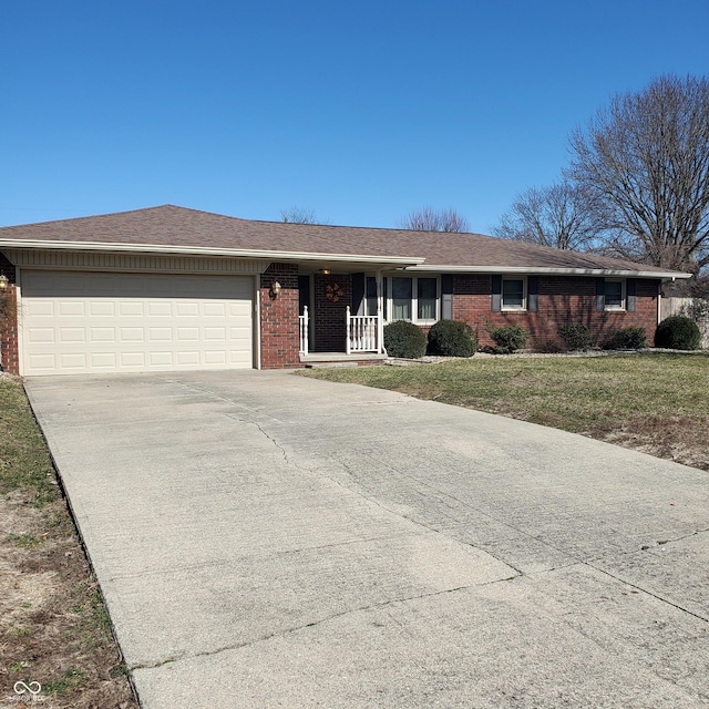 ranch-style home featuring brick siding, a porch, concrete driveway, an attached garage, and a front yard