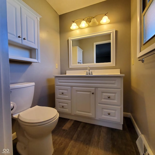 bathroom featuring visible vents, toilet, vanity, wood finished floors, and baseboards