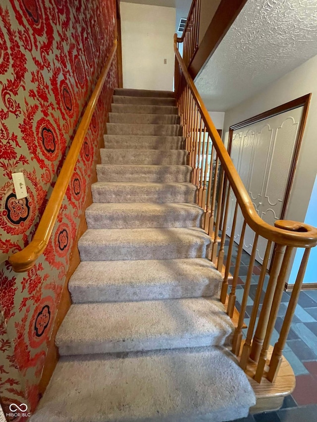 stairway featuring a textured ceiling