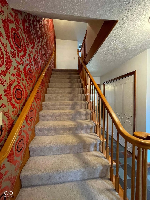 stairs featuring a textured ceiling