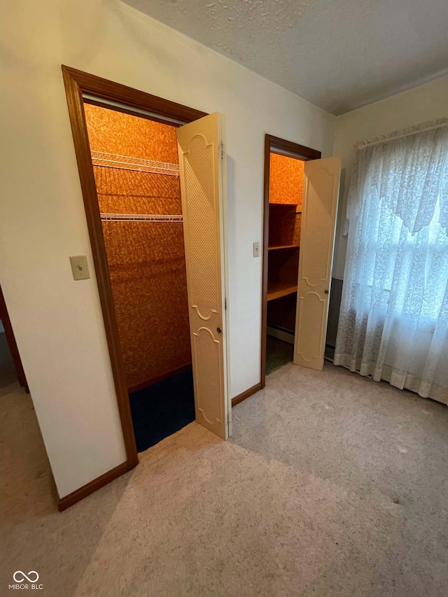 unfurnished bedroom with light colored carpet, a textured ceiling, and baseboard heating