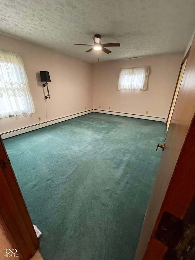 unfurnished room with baseboard heating, a healthy amount of sunlight, a textured ceiling, and carpet flooring