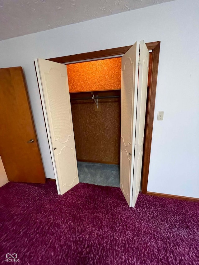 unfurnished bedroom with dark colored carpet and a closet