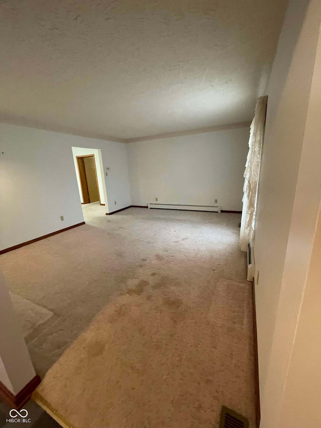 unfurnished room featuring a baseboard heating unit, light colored carpet, and a textured ceiling