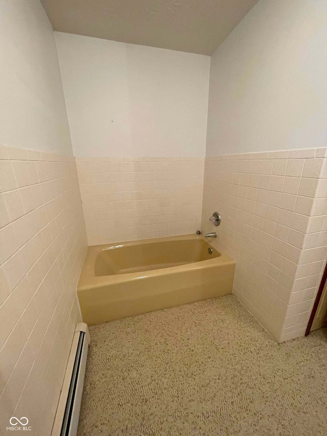 bathroom featuring a tub, tile walls, and baseboard heating