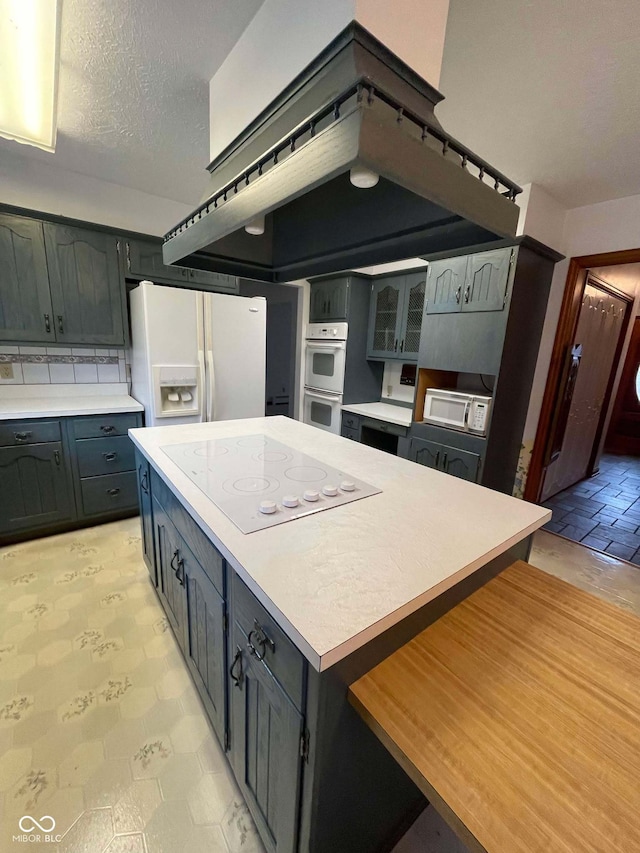 kitchen featuring a center island, a textured ceiling, and white appliances