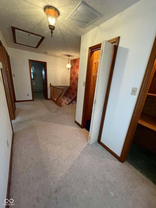 hall featuring light carpet and a textured ceiling